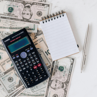 Financial office's toolkit; money, calculator, and a notepad.